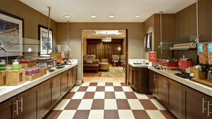 Une cuisine d’hôtel avec un comptoir d’enregistrement, un espace buffet et un coin salon à l’arrière-plan.