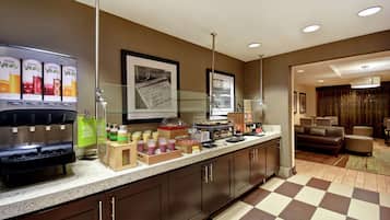 A hotel kitchen with a juice bar, a refrigerator, and a coffee station.