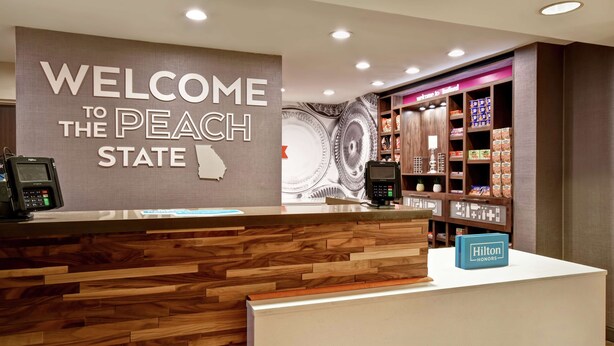 Un comptoir d’accueil avec une pancarte indiquant « Bienvenue dans l’État de la pêche », un espace d’accueil en bois et une présentation de produits locaux.
