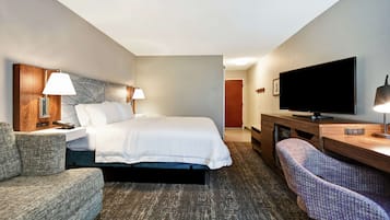 A hotel room with a bed, a desk, a television, and a chair.