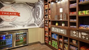 Un espace dédié aux collations et aux produits divers, avec un assortiment de produits emballés, un mur décoratif orné d’une inscription « GÂTERIES », et un distributeur automatique.