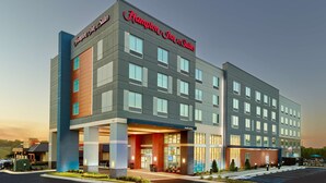 Um hotel Hampton Inn & Suites com design moderno, apresentando uma entrada espaçosa, vários andares e estacionamento.