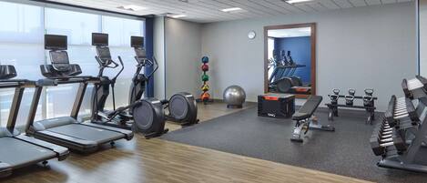 Un gimnasio con cintas de correr, pesas y pelotas de ejercicio.