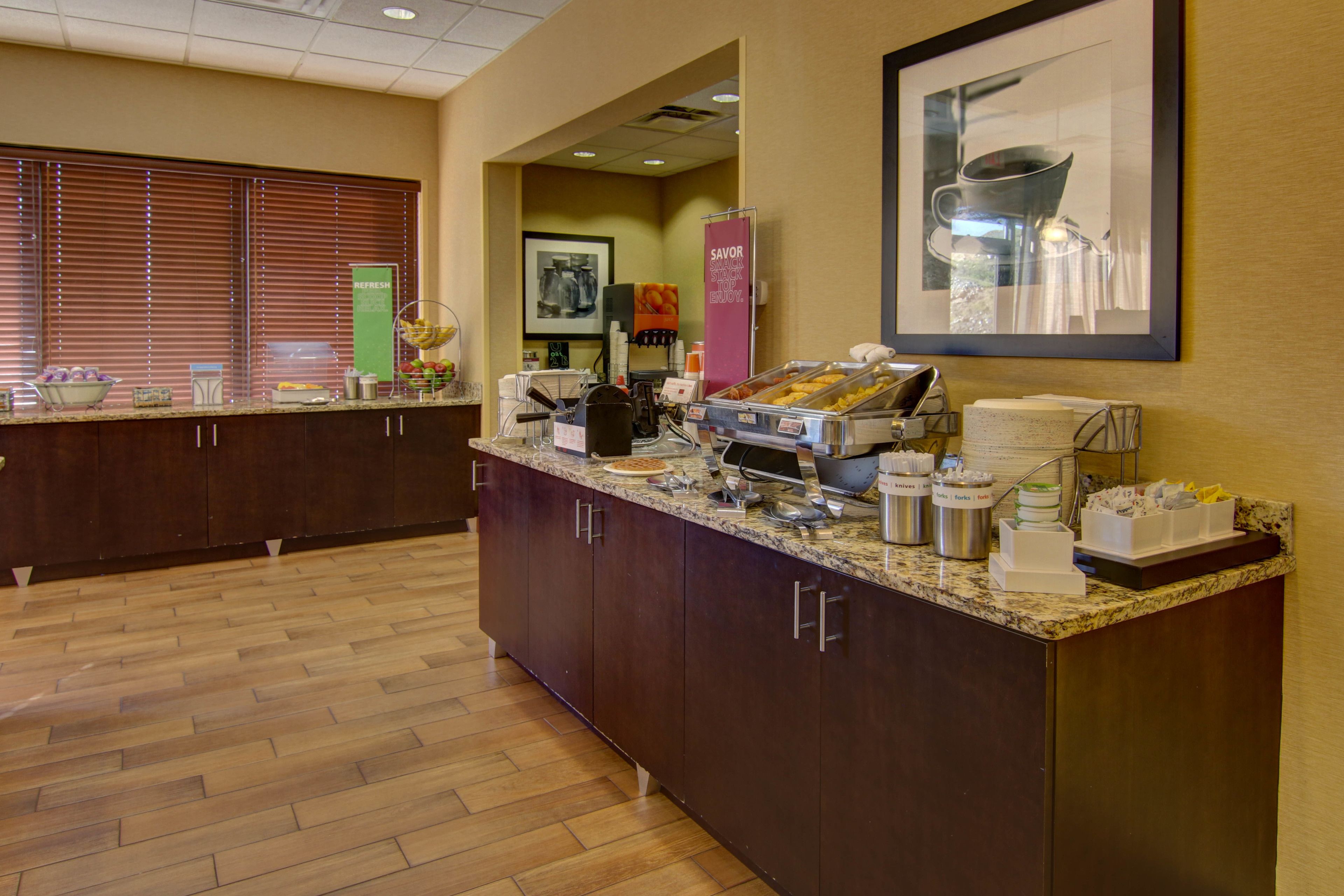 Un espace pour le petit-déjeuner à l’hôtel, avec un comptoir en marbre, divers aliments et un coin café.