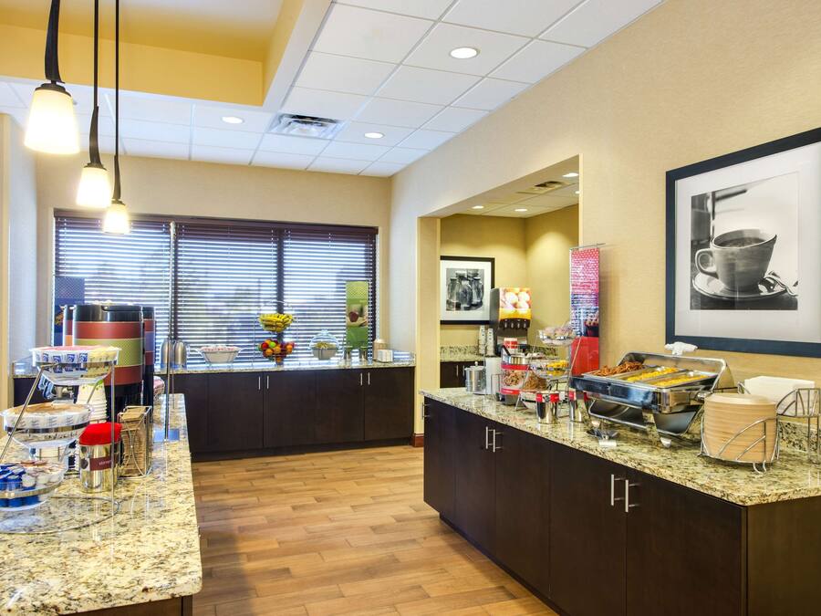 A hotel kitchen with buffet setup, including various food stations and a large window with blinds.