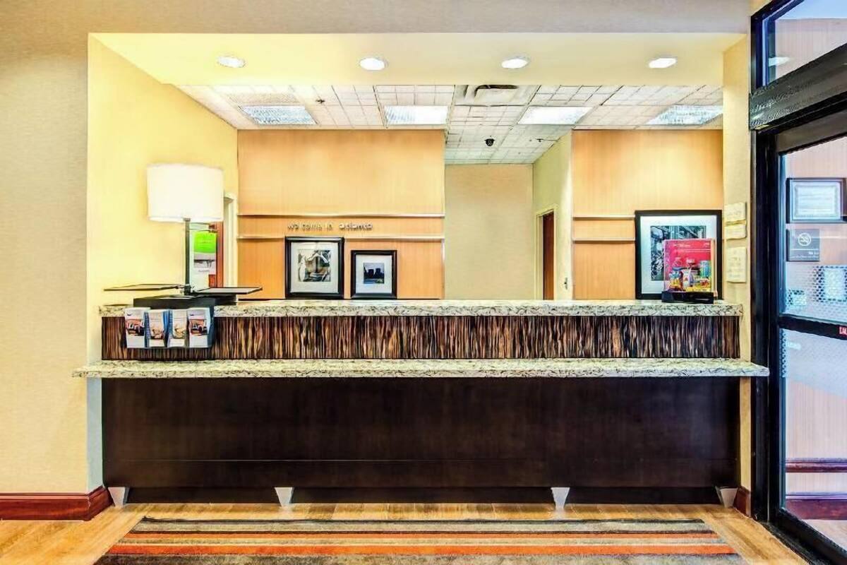 A reception desk with a dark wood finish, a framed welcome sign, and a lamp.