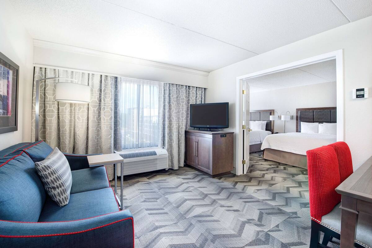 A hotel room with a sofa, TV, desk, and a bed.