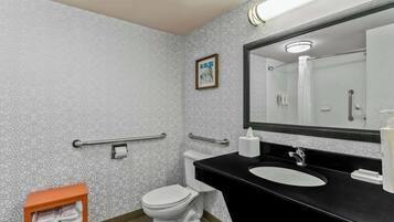 Et moderne badeværelse med tapetseret væg, et hvidt toilet, en sort vask og et spejl.