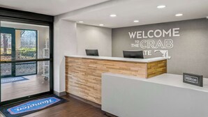 Un mostrador de recepción con un cartel que dice "WELCOME THE CRAB", un mostrador de madera y un cartel de "Hilton Honors".