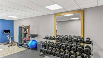 A gym with exercise equipment, a mirror, and a wall-mounted TV.