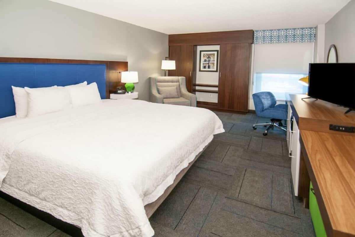 Een hotelkamer met een groot bed, een bureau met een televisie, een stoel en een raam.