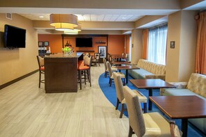 A hotel lobby with a bar area, seating arrangements, and a television screen. - Hampton Inn Metairie (Metairie)