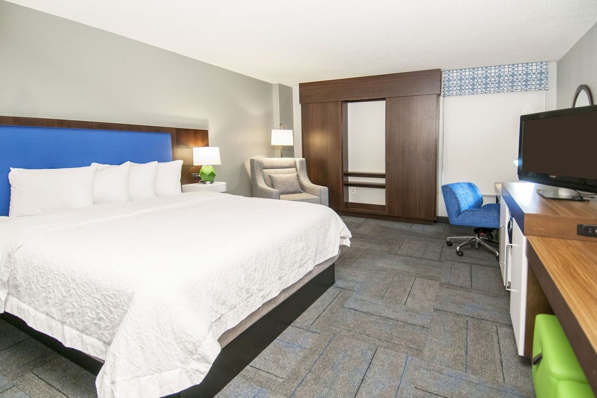 Een hotelkamer met een bed, een bureau met een computer, een stoel en een televisie.