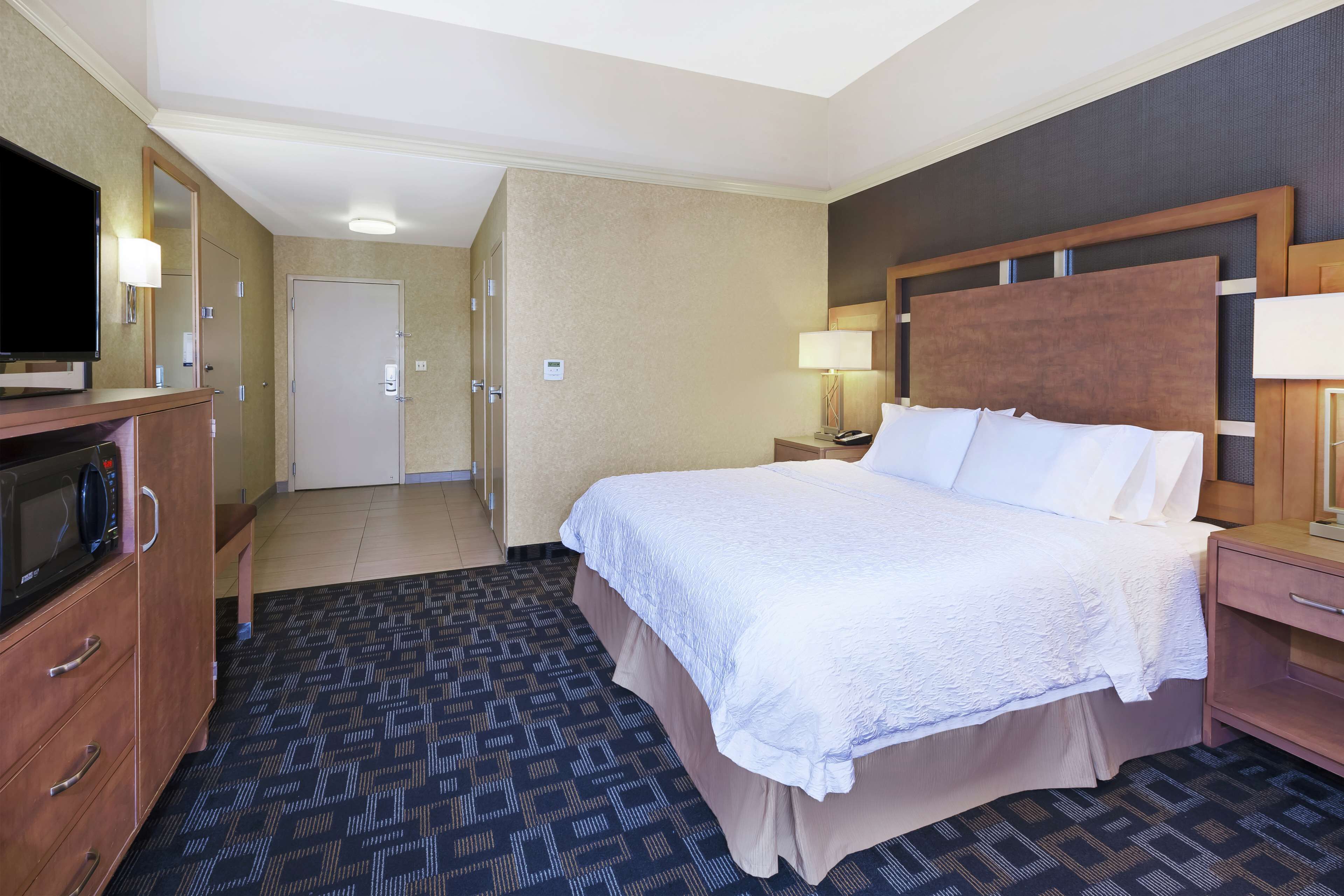 Une chambre d’hôtel comprenant un lit, une table de chevet, une lampe, une télévision et une armoire.