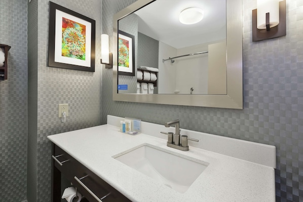 A modern bathroom with a large mirror, a white sink, and a towel rack.