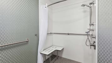 A shower area with a grab bar, a showerhead, and a shower seat.