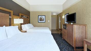 A hotel room with two beds, a television, a desk, and a cabinet.