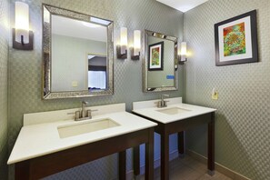 A bathroom with two sinks, mirrors, and wall-mounted light fixtures.