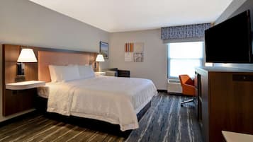 A hotel room with a large bed, bedside lamps, a flat-screen TV, a desk, and a chair.