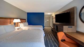Habitación de hotel con dos camas, un escritorio, un televisor y una silla.