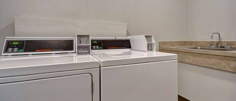 A laundry area with two commercial dryers and a sink.