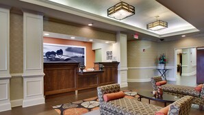 A lobby with a reception desk, patterned sofas, a coffee table, and a decorative plant. - Hampton Inn Warner Robins (Warner Robins)