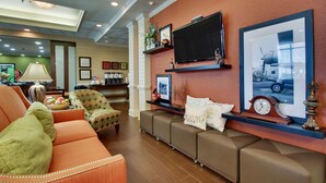 A modern living room with a sofa, armchairs, a coffee table, a flat-screen TV, and a fireplace. - Hampton Inn Warner Robins (Warner Robins)
