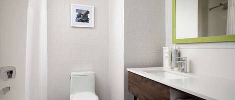 A modern bathroom with a toilet, shower, and sink.