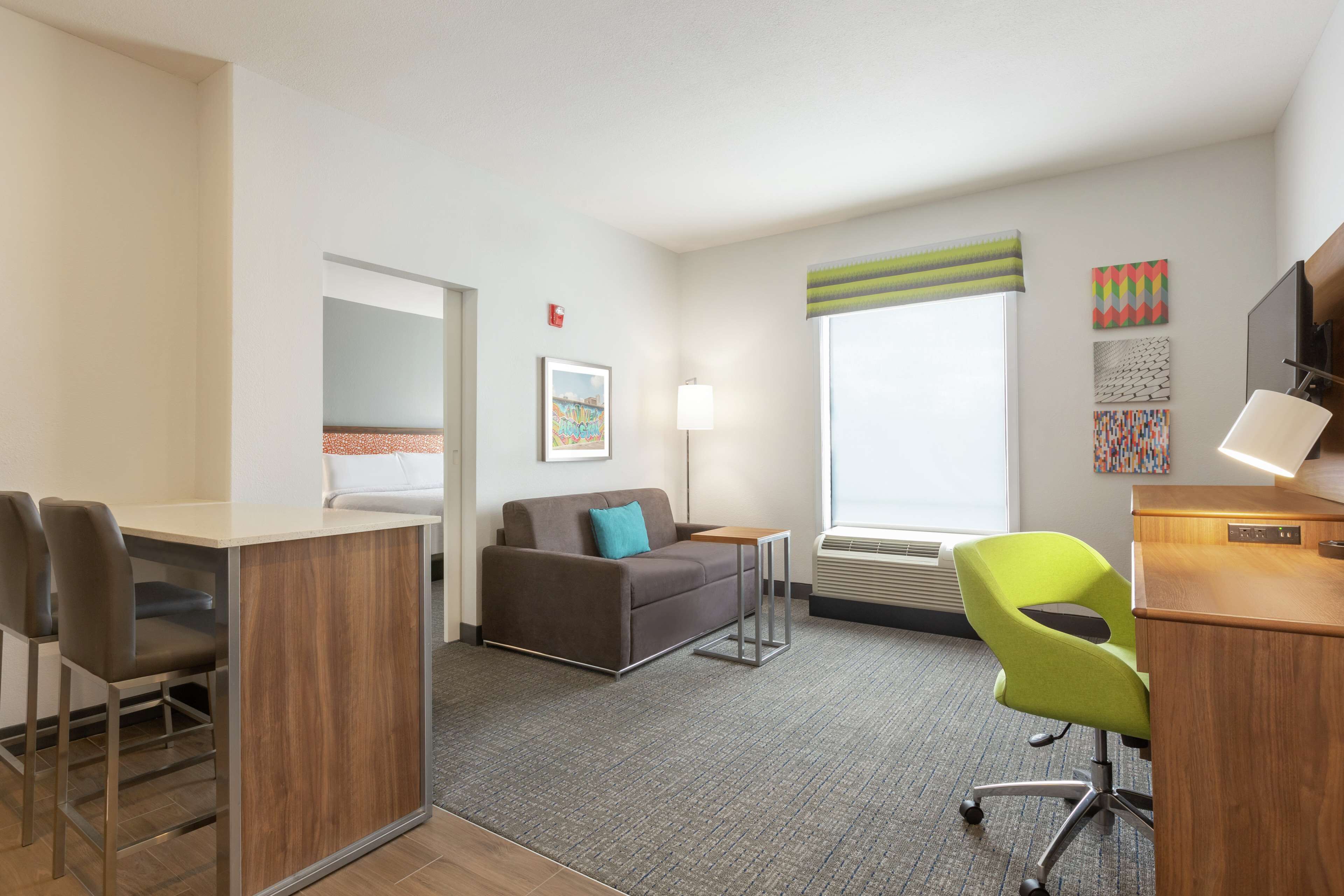 A modern hotel room with a sofa, a desk, a chair, and a small table.
