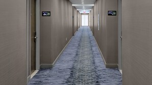 A hotel hallway with carpeted floors, beige walls, and doors marked with room numbers. - Hampton Inn & Suites Houston-Cypress Station (Houston)