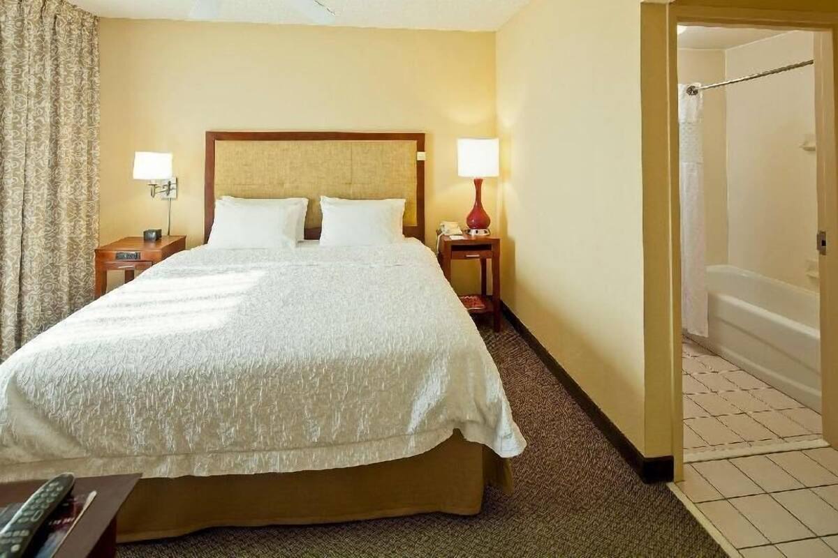 Een hotelkamer met een groot bed, twee bedlampen, een nachtkastje en een zichtbare badkamedeur.