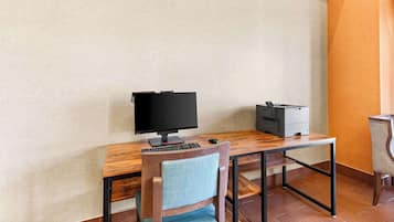 Un espace de travail comprenant un écran d’ordinateur, un clavier et une imprimante, le tout posé sur un bureau en bois.