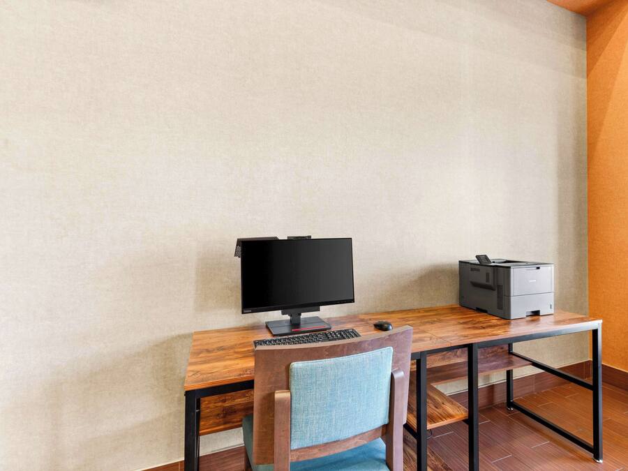 Un espace de travail comprenant un écran d’ordinateur, un clavier et une imprimante, le tout posé sur un bureau en bois.