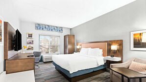 A modern hotel room with a large bed, a desk, a chair, a sofa, and a TV. - Hampton Inn & Suites Phoenix-Goodyear (Goodyear)