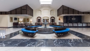 A spacious lobby with a central fountain, seating areas, and a reception desk. - Barceló Aruba - All Inclusive (Noord)