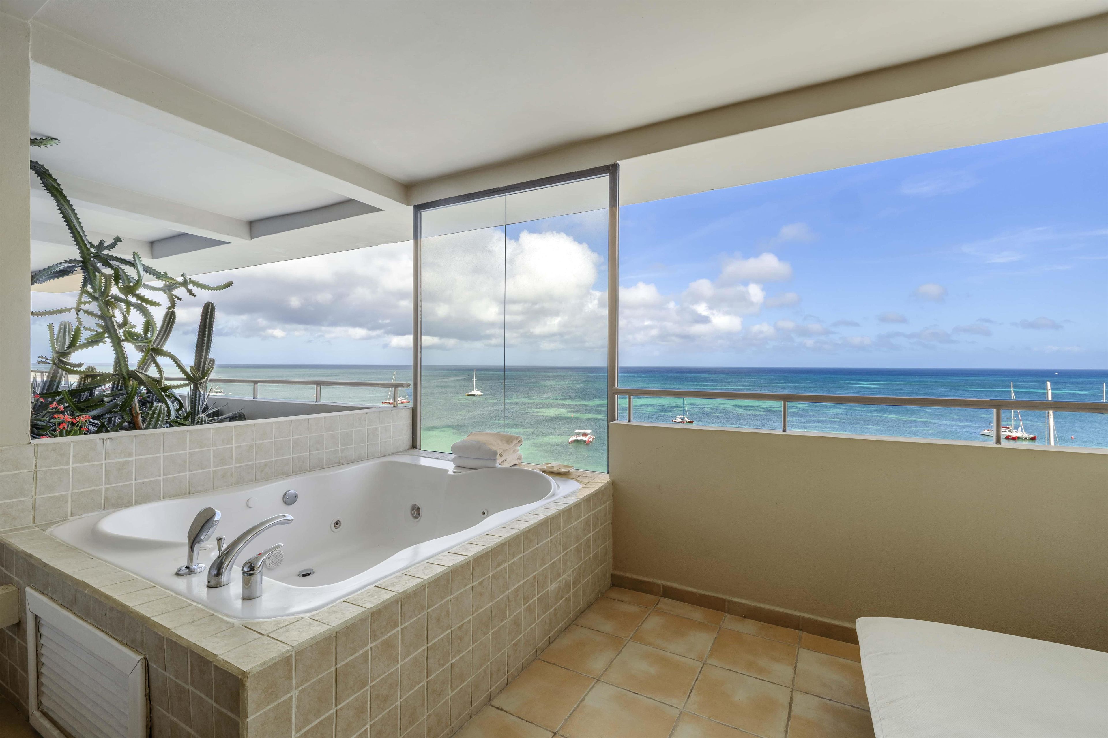 A bathroom with a large bathtub, a shower, and a view of the ocean.