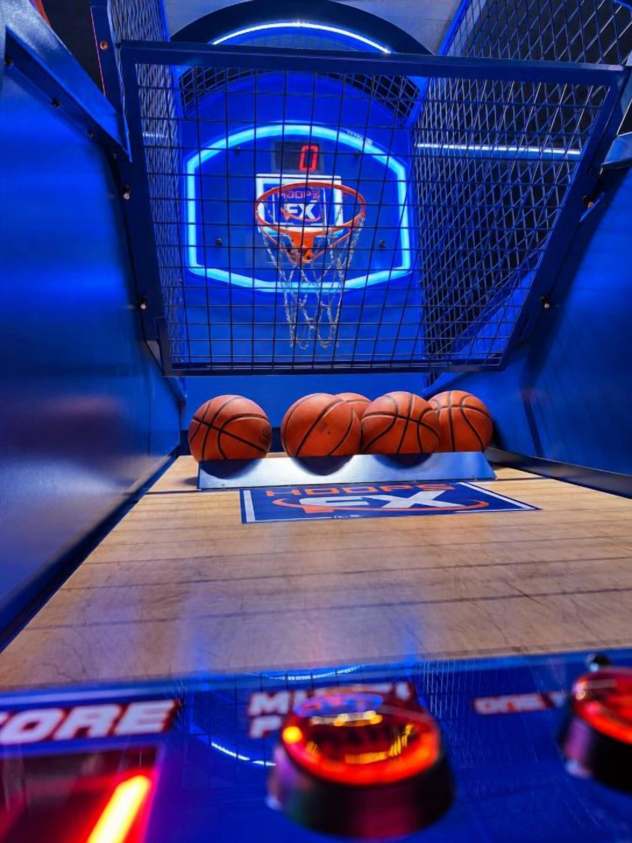 Una cancha de baloncesto con un aro, tres balones de baloncesto y un marcador.