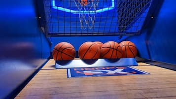Una cancha de baloncesto con un aro, tres balones de baloncesto y un marcador.
