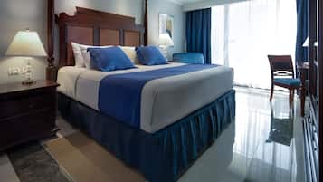 Habitación de hotel con una cama grande, una mesita de noche, un escritorio, una silla y vistas al exterior.