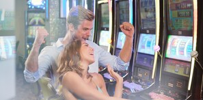 Une zone de casino avec plusieurs machines à sous et une personne qui en utilise une.