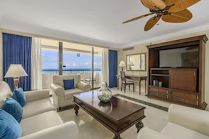 A hotel room with a balcony, a television, a dining table, and a sofa. - Barceló Aruba - All Inclusive (Noord)