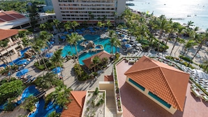 A resort with multiple swimming pools, palm trees, and a view of the ocean. - Barceló Aruba - All Inclusive (Noord)