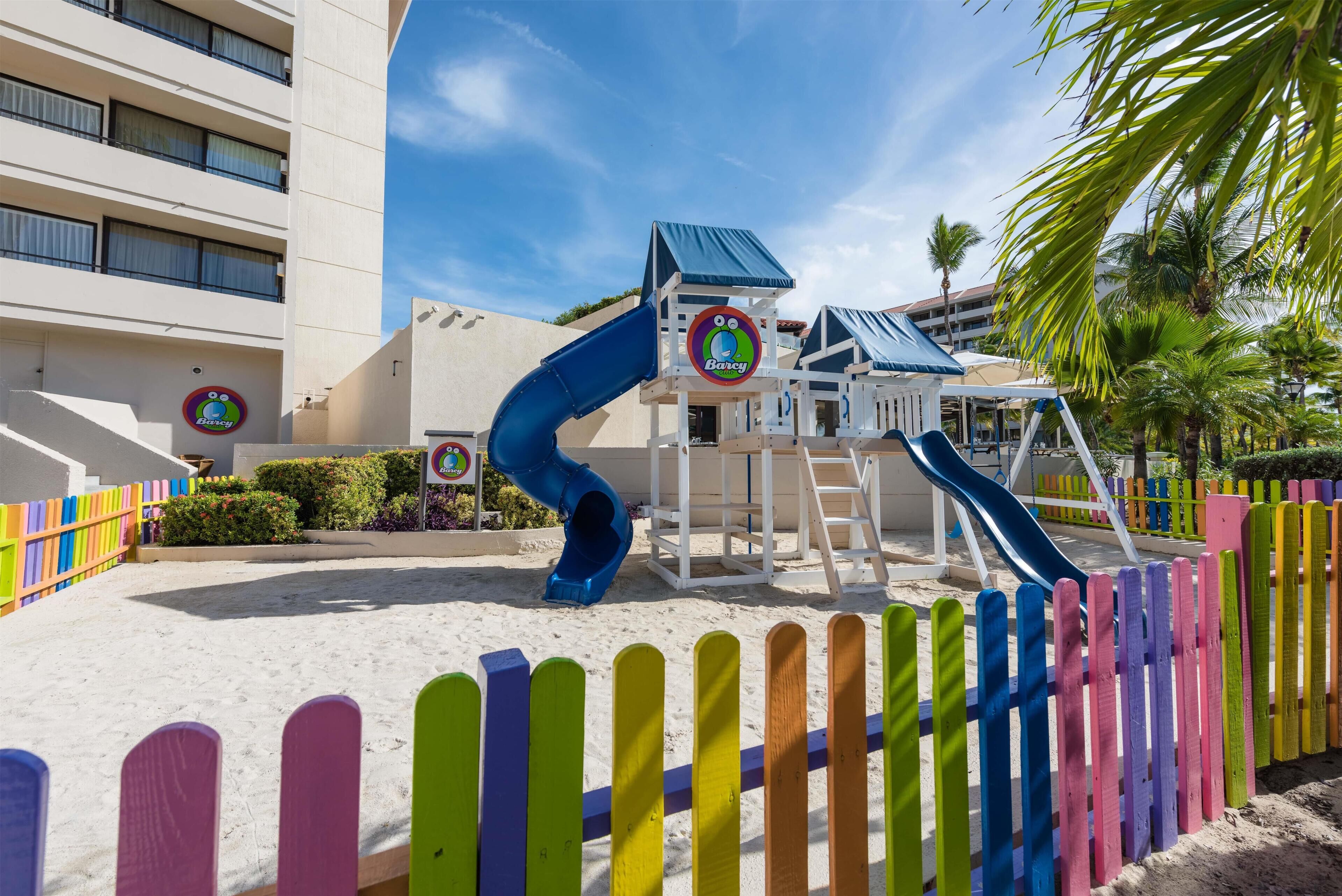 A children's play area with slides and a colorful fence.