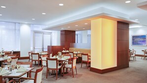 A modern dining area with multiple tables and chairs, a central seating area, and a large artwork on the wall. - InterContinental Suites Hotel Cleveland by IHG (Cleveland)