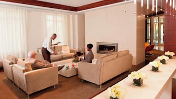 A hotel lobby with sofas, a fireplace, and a reception area.