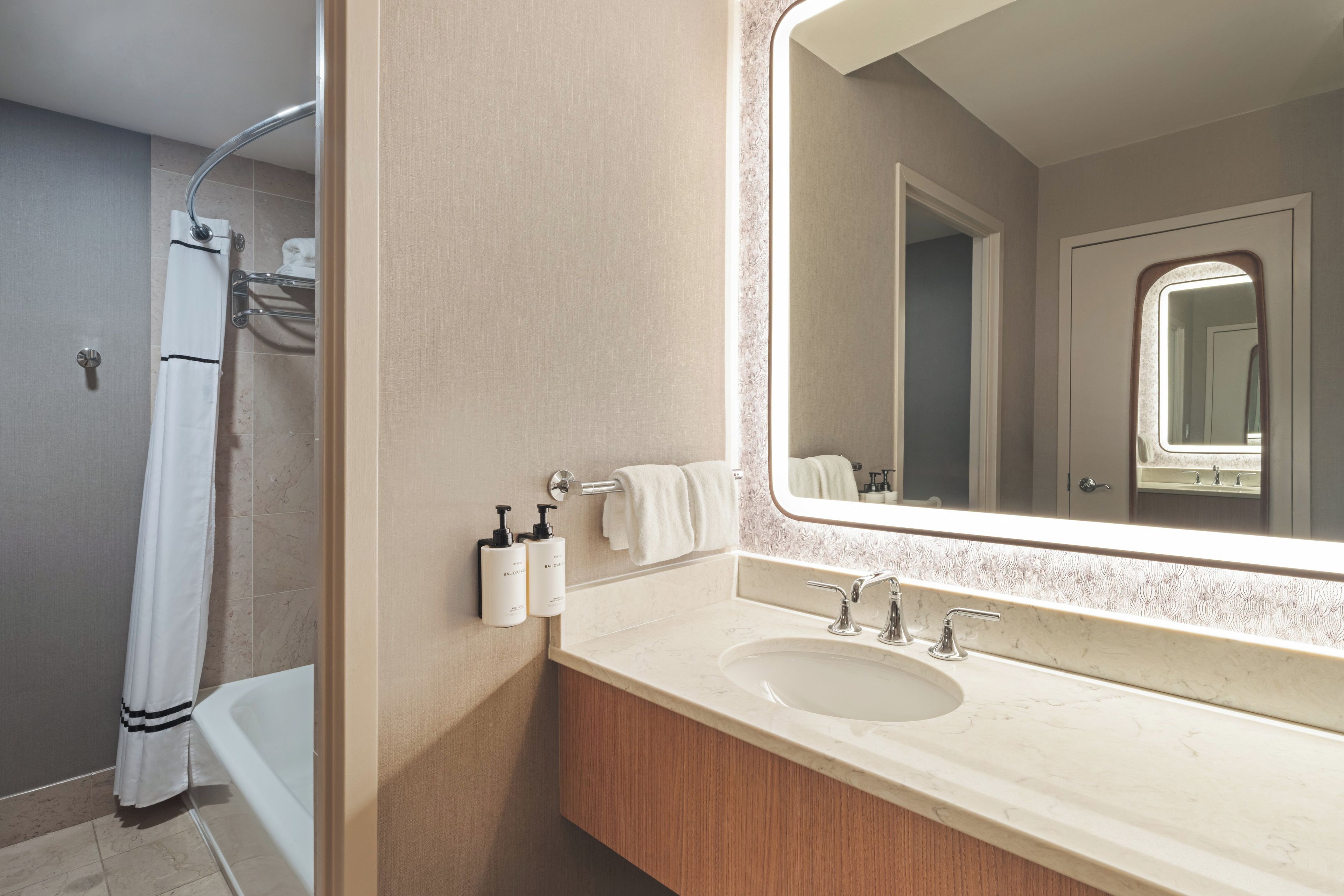 A bathroom with a bathtub, a sink, a mirror, and a towel rack.