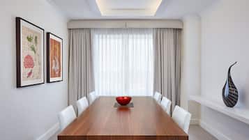 A conference room with a long wooden table, white chairs, a red bowl centerpiece, and framed artwork on the wall.