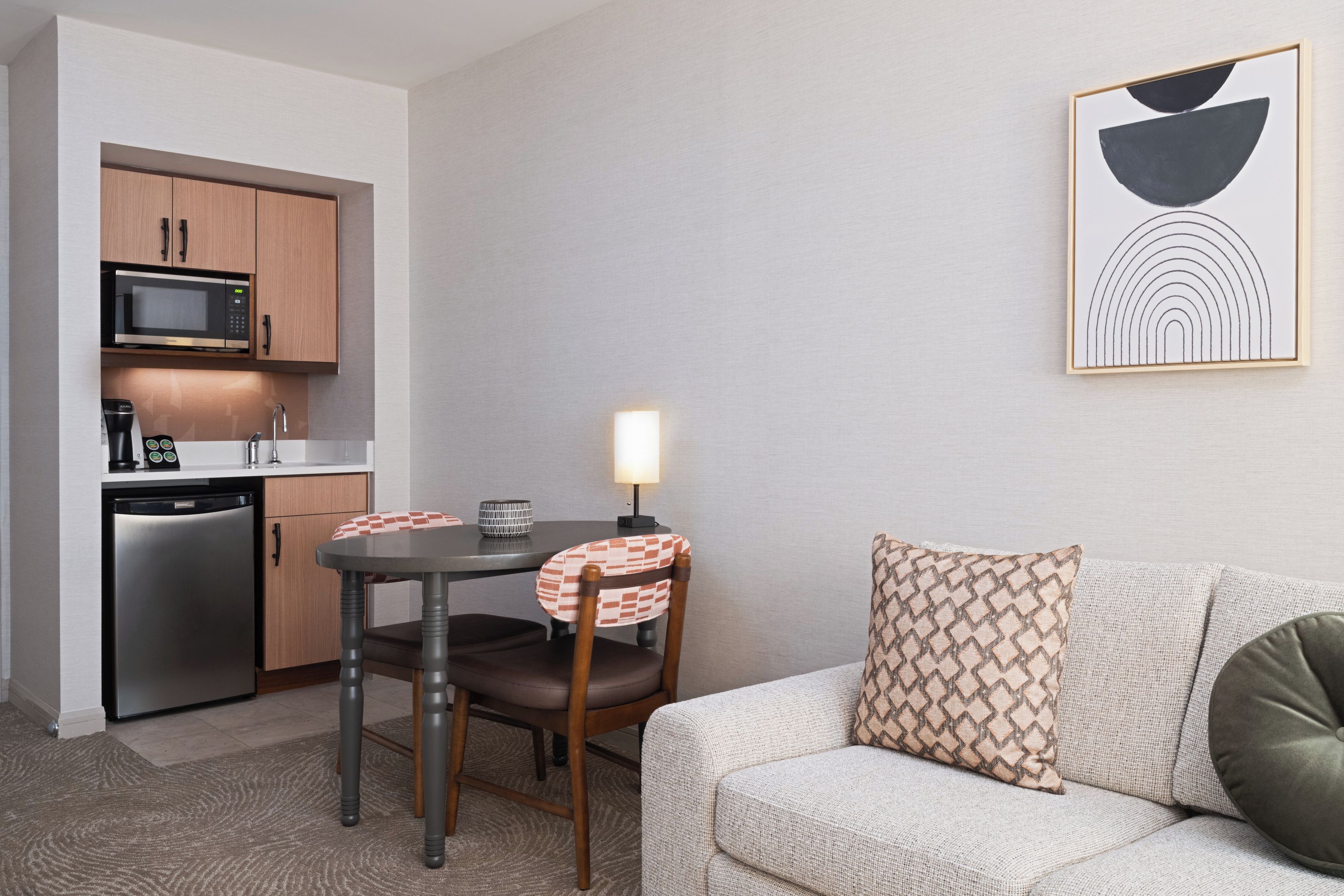 A compact living space with a kitchenette, a dining area, and a seating area with a sofa and a table.
