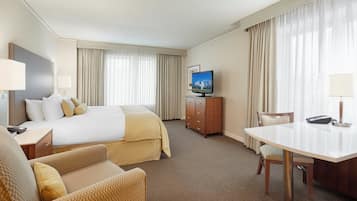 Une chambre d’hôtel équipée d’un lit, d’un bureau, d’une chaise, d’une télévision et d’une commode.