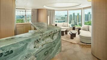 A modern hotel lobby with a marble reception desk, a sofa, and a coffee table. Large windows offer a city view.